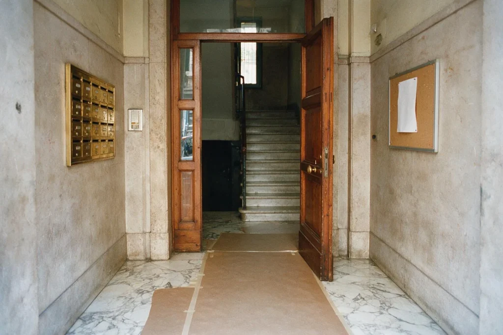 L'androne di un palazzo con pavimento in marmo protetto da carta, cassette delle lettere e bacheca