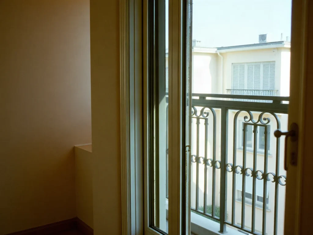 Una porta finestra in alluminio a vetro singolo che dà su un balcone con la ringhiera in ferro
